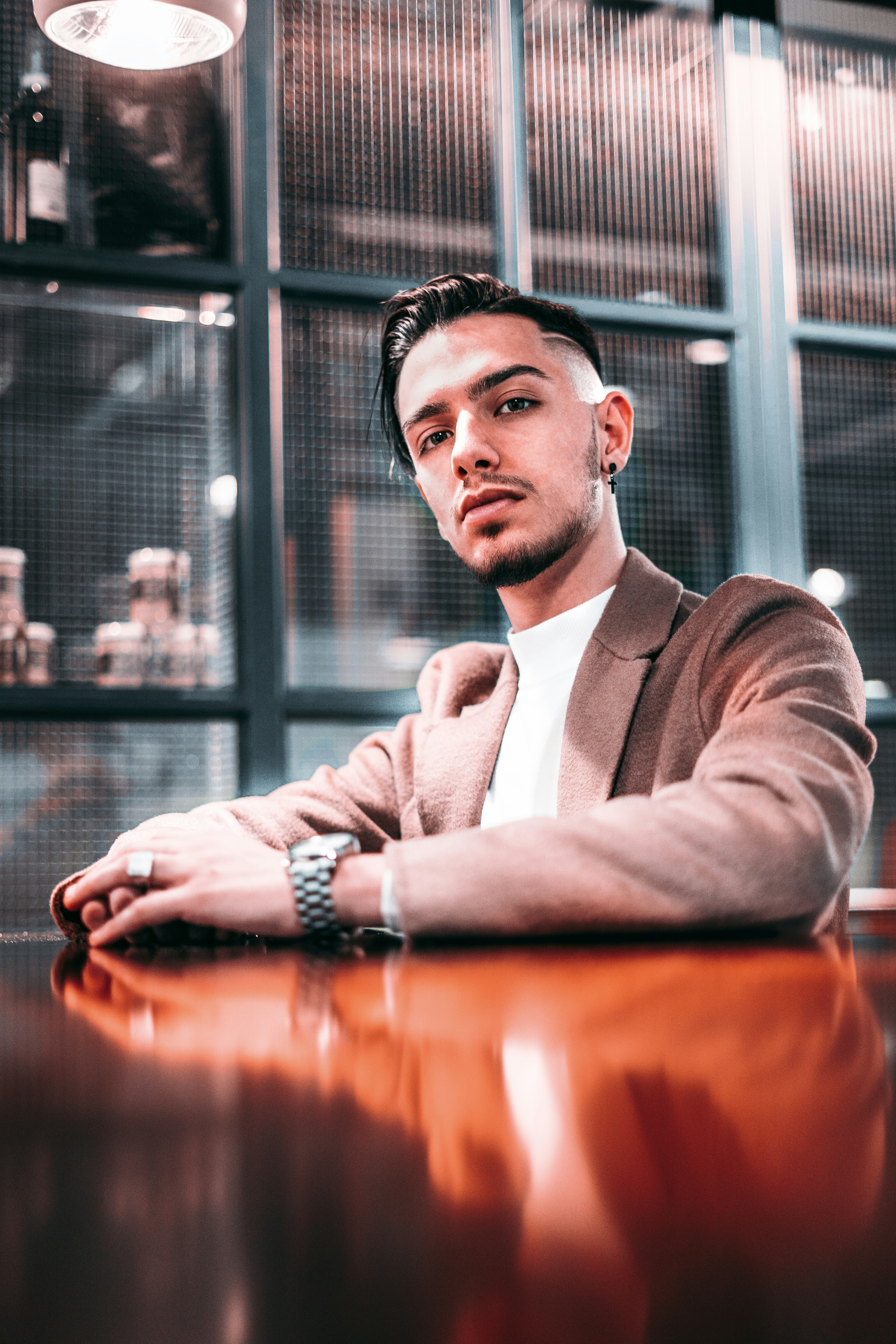 man wearing suit jacket leaning on wooden table